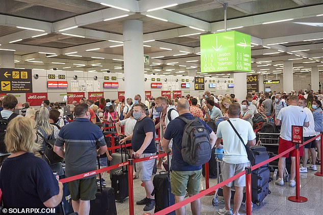 一群人站在一个房间里：昨天，马略卡岛帕尔马机场的旅客（如图）告诉《泰晤士报》，他们为航班和 Covid 抗原测试支付了数百甚至数千英镑的额外费用，以便早日结束假期返回并击败最后期限